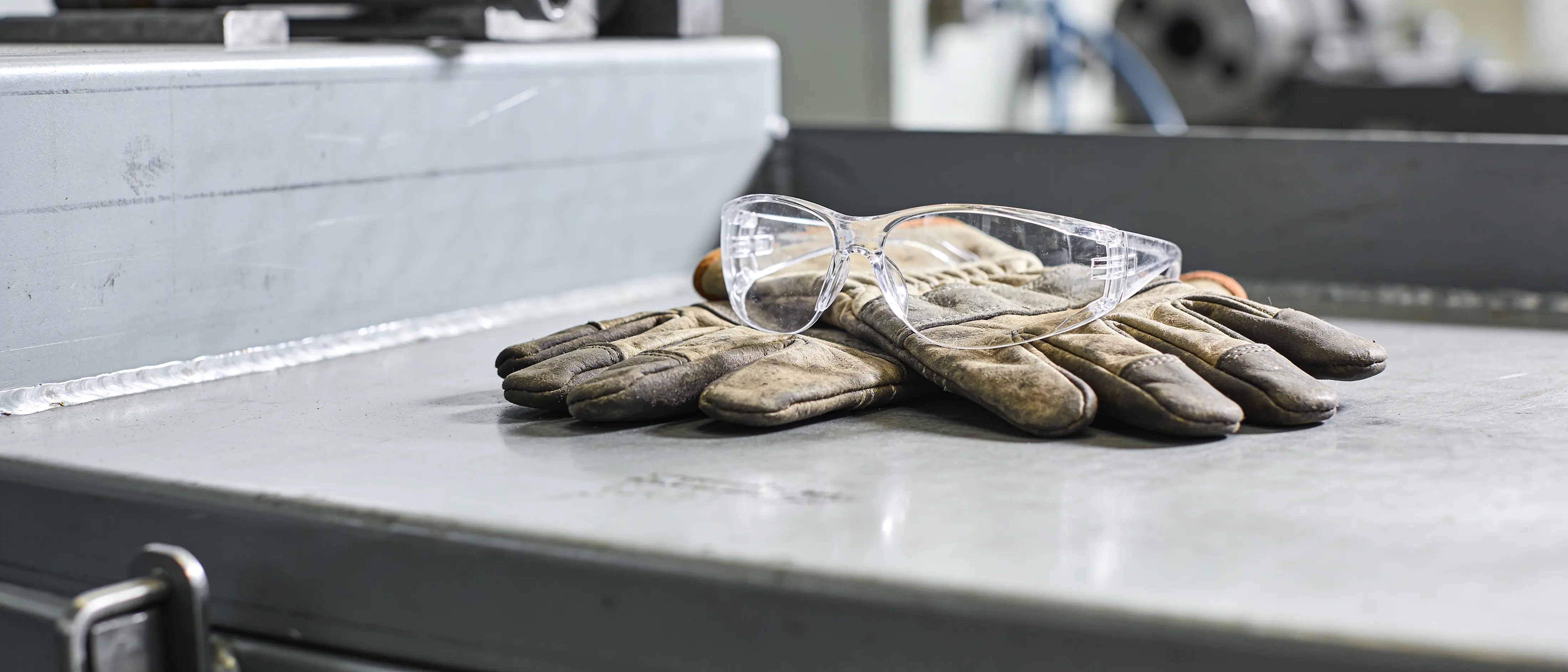 Arbeitshandschuhe und Schutzbrille auf einer Werkbank
